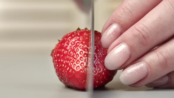 Closeup Woman Fingers Cutting Whole Fresh Red Strawberry to Half on Wooden Kitchen Table Use Knife