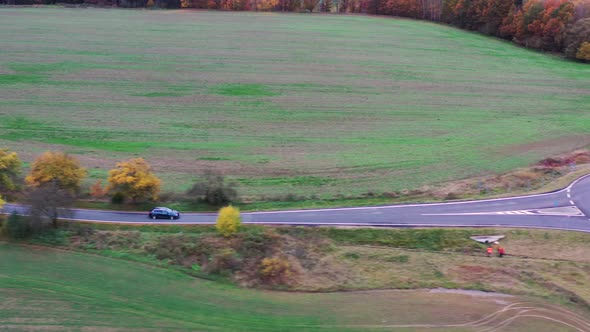 Aerial View of Lonely Car on Countryside Road in Autumn Approaching Roundabout. Bohemian Mountains V