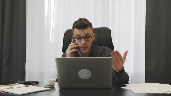 Angry businessman talking on phone in modern office. Business concept