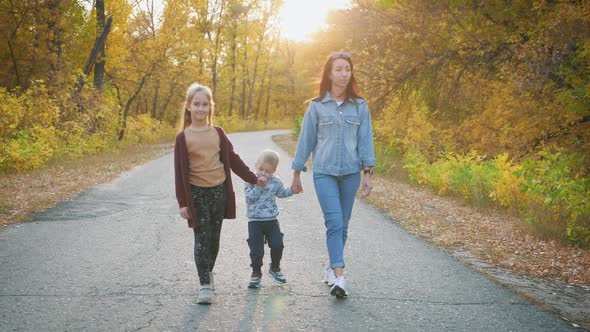 Mother and Two Children Walking in the Park and Enjoying the Beautiful Autumn Nature