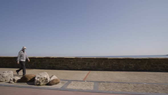 Sitting bench and people walking on coastal pathway in San Sebastian