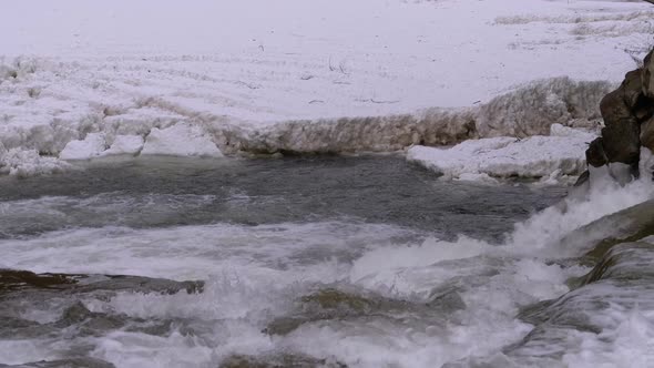 Rapid Flow of Water From a Mountain Creek and Stone Rapids with Snow in Winter. Waterfall. Slow