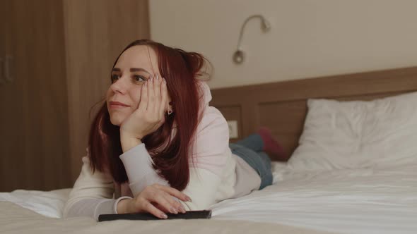 Young Woman in Casual Clothes Lying on Bed and Watching Tv