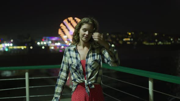 Woman walking on Santa Monica Pier, at night alt