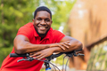 latin amerixan man in casual clothes smiling while leaning on his bike - PhotoDune Item for Sale