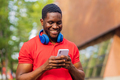 young afro american man with headphones on neck using smartphone in summer park - PhotoDune Item for Sale