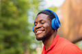 african american man in red t-shirt listening music in blue headphones - PhotoDune Item for Sale