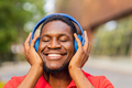 african american man in red t-shirt listening music in blue headphones - PhotoDune Item for Sale
