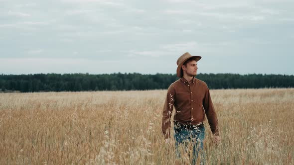 Farmer in Hat in Young Wheat Field and Examining Crop. Man Walking Through Wheat Field. Wheat Field