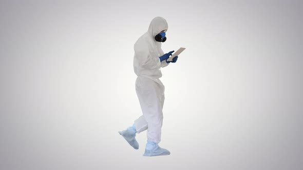 Scientist or Docrot Wearing Biohazard Suits and Protective Masks Using Digital Tablet While Walking