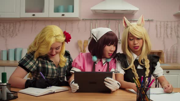 Pretty Multiracial Female Cosplayers with Tablet Pc Choosing Cosplay Costumes