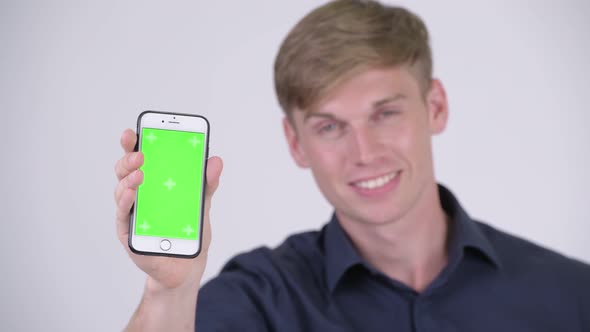 Happy Young Handsome Blonde Businessman Showing Phone