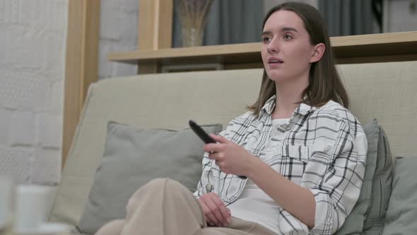 Relaxed Young Woman Sitting on Sofa and Watching TV 