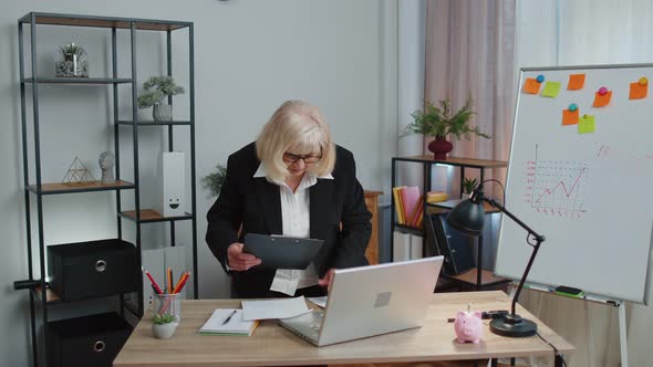 Senior Business Woman Examining Graphs Analyzing Managing Finance Documents Report at Home Office