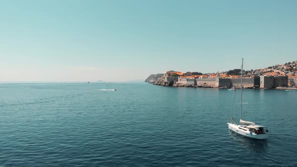 Sailboat floating on sea along coastal town on sunny day