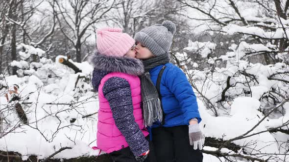 Children a Boy and a Girl Hug and Kiss in the Winter in the Cold in the Snowcovered Forest