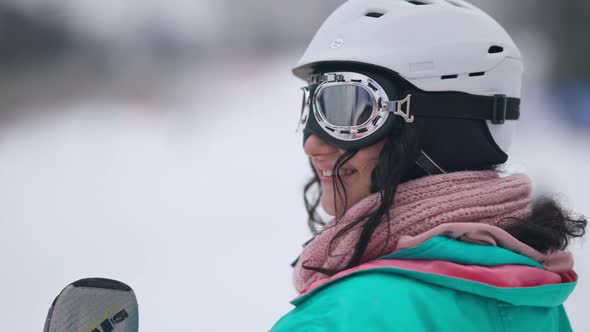 Closeup Side View of Happy Smiling Young Woman in Ski Goggles and Helmet Looking Away Standing at