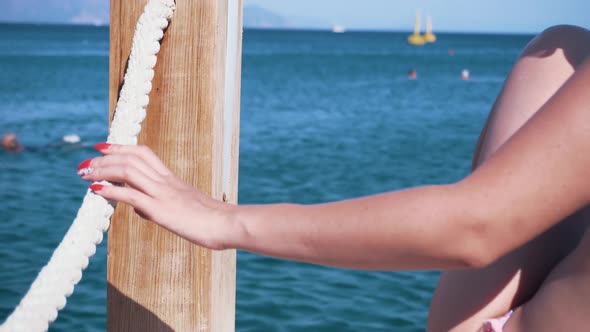 Girl Holding Rope On Pier. Woman Hand Holding Rope And Relish Holiday Vacation At Sea.