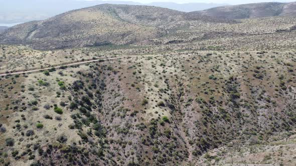 Drone video of Arizona mountains and desert with a car driving in the distance.