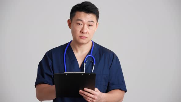 Concentrated Asian doctor collects anamnesis