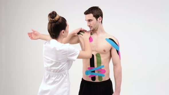 Shoulder treatment with kinesio tape. Physiotherapist applying elastic therapeutic tape