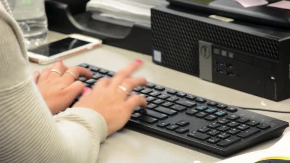 Close up of woman’s hands while typing on computer keyboard wearing a sweater