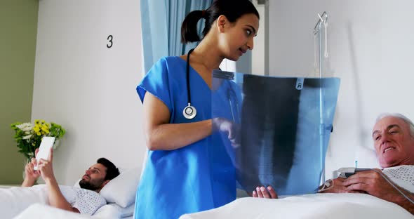 Female doctor discussing x-ray report with male senior patient in the ward