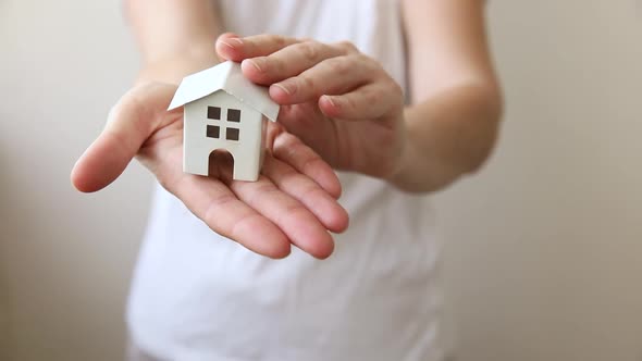 Woman Hand Holding Toy Model House Isolated on White Background