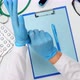 doctor in a white coat sits at a work table and puts blue latex gloves  - VideoHive Item for Sale