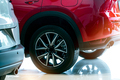 Closeup wheel of red car parked in showroom. Wheel and tire of new car. Car dealership business - PhotoDune Item for Sale