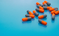 Orange-gray antibiotic capsule pills on blue background. Antibiotic drug resistance. Pharmaceutical - PhotoDune Item for Sale
