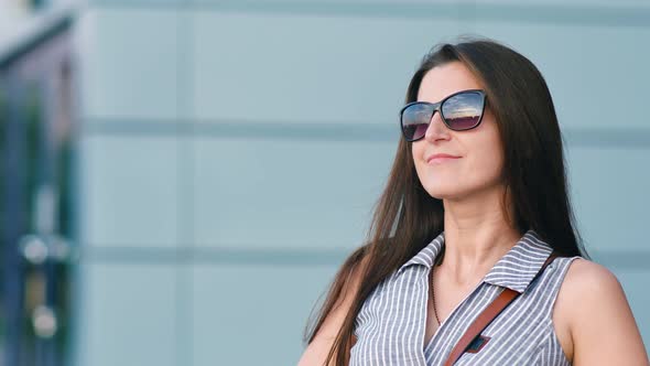 Lovely Woman Standing Near Modern Building Enjoying Outdoor Raising Hands and Playing with Hairs