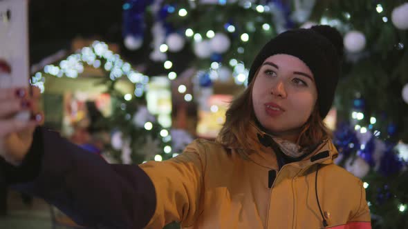 Young Woman Taking Photo with Mobile Phone on Christmas Market