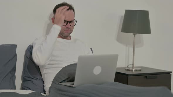 Casual Man Reacting to Loss on Laptop in Bed