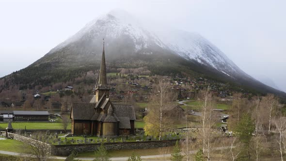 Scenic View Of Lom Stave Church Against Massive Snowy Mountain On Wintertime In Norway. Aerial Drone