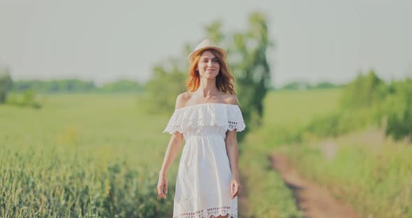 Happy Girl in a White Dress and Hat Goes on a Sunny Day