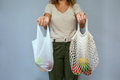 Unrecognizable woman comparing reusable mesh bag and disposable plastic bag with fruits - PhotoDune Item for Sale