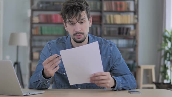 Pensive Man Thinking While Reading Documents Paperwork