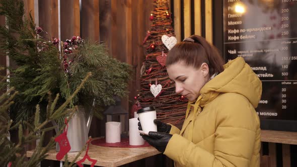 Beautiful Woman Drinks Coffee in a Cafe on the Street