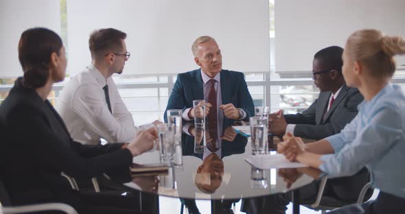 Multiethnic Team Listening to Boss at Business Meeting in Conference Room