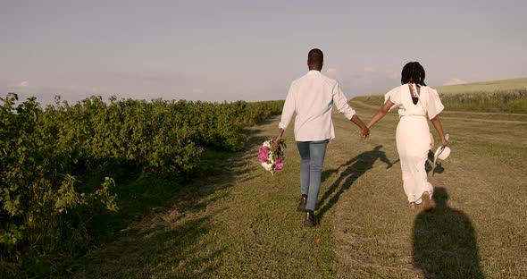 Black Newlyweds Walking with Bouquet in Nature