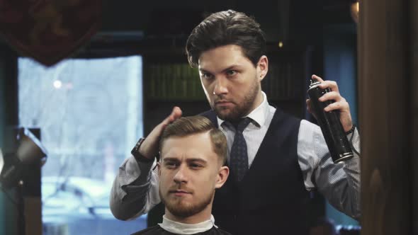 Professional Barber Using Hairspray Styling Hair of a Young Man