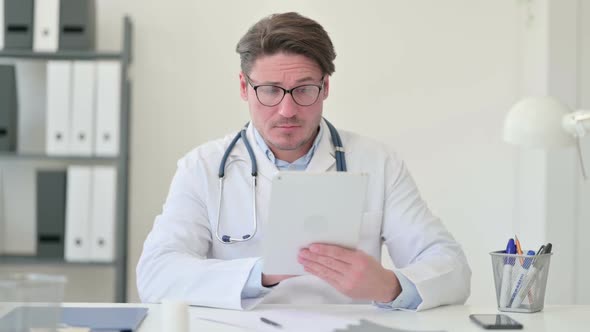 Middle Aged Male Doctor Using Digital Tablet