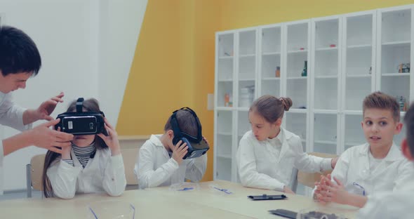 Schoolgirl and Schoolboy in the Classroom Watching in Virtual Reality Glasses