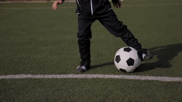 Closeup of Little Boy Soccer Player Trains on a Soccer Field with Green Grass