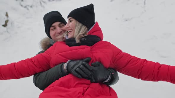 Smiling Couple Sliding on Bumper Tube in Winter Forest