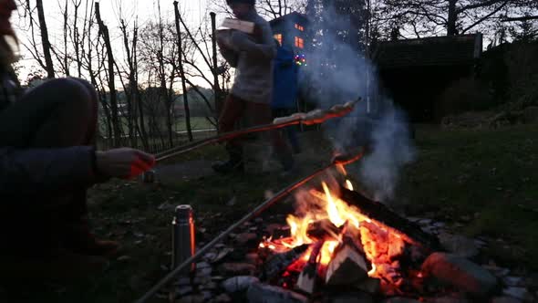 Family at bonfire, boy bringing firewood