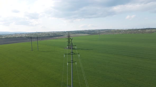 Aerial View of High Voltage Lines and Power Pylons in a Flat and Green