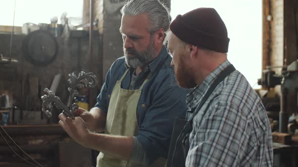 Two Blacksmiths Discussing Iron Details at Work