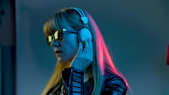 Woman with Headphones Listening to Music and Dancing in Neon Light at Studio